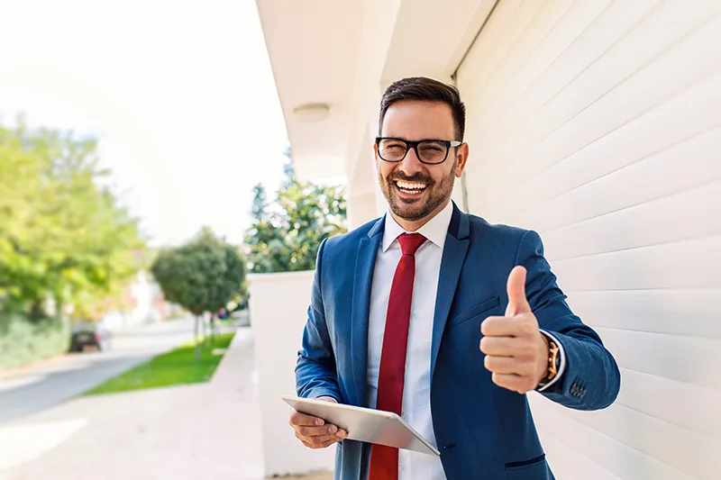 Real estate agent with a tablet in front of a property